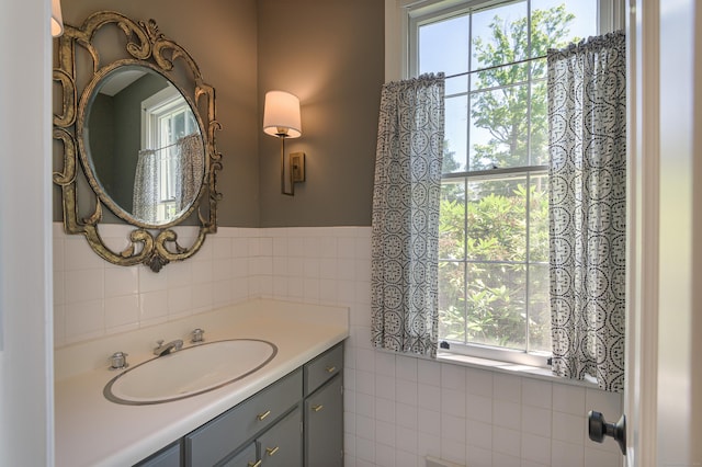 bathroom with a healthy amount of sunlight, tile walls, and vanity