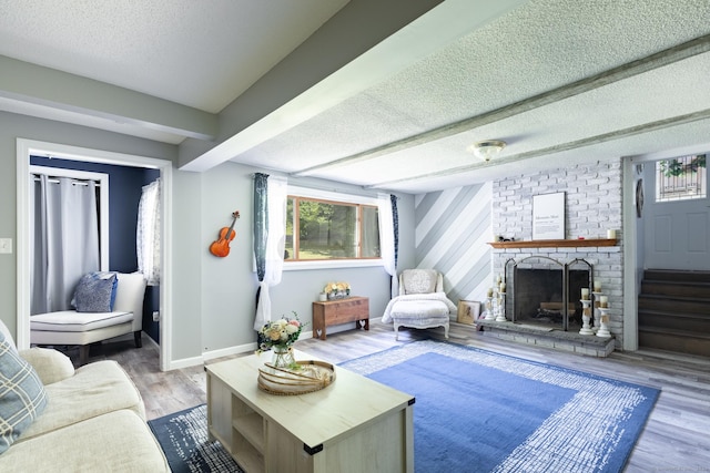 living room with a textured ceiling, wood finished floors, beam ceiling, and baseboards