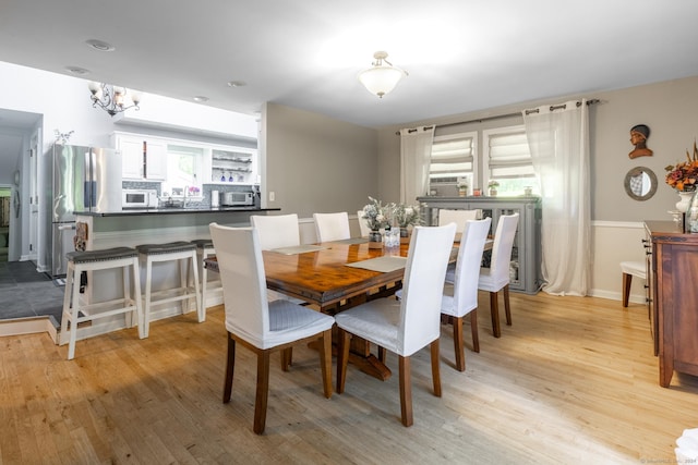 dining room featuring a healthy amount of sunlight, a notable chandelier, and light wood finished floors