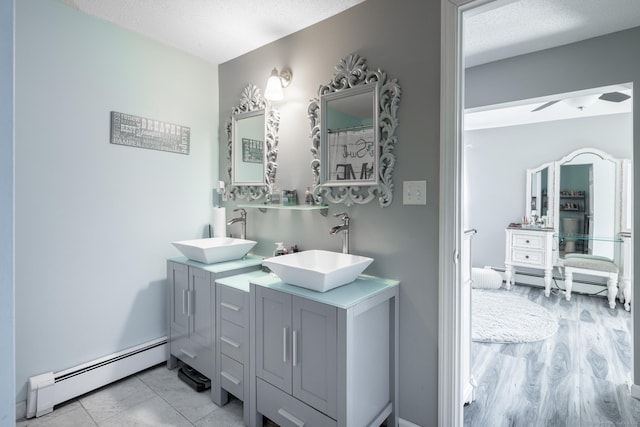 bathroom featuring a textured ceiling, a baseboard heating unit, and a sink