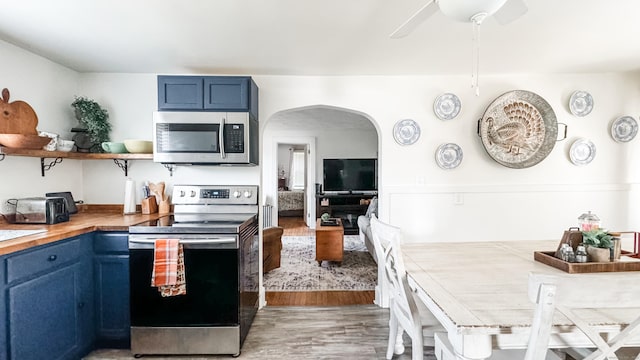 kitchen featuring appliances with stainless steel finishes, ceiling fan, wood-type flooring, and blue cabinetry