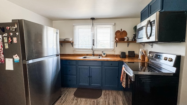 kitchen with decorative light fixtures, stainless steel appliances, sink, blue cabinetry, and dark wood-type flooring