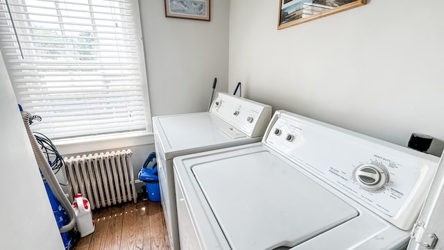 clothes washing area featuring washing machine and dryer, dark hardwood / wood-style flooring, and radiator