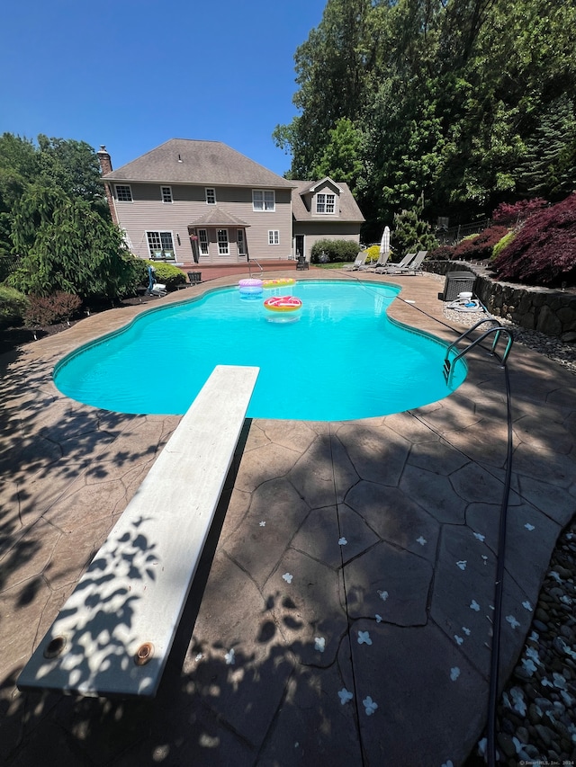 view of pool with a diving board and a patio