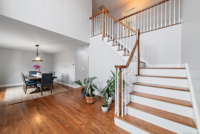 stairway featuring a high ceiling and hardwood / wood-style flooring