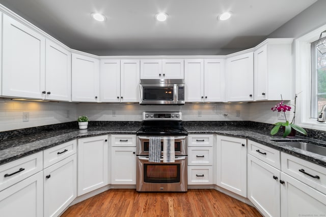 kitchen with light hardwood / wood-style floors, white cabinetry, sink, and appliances with stainless steel finishes