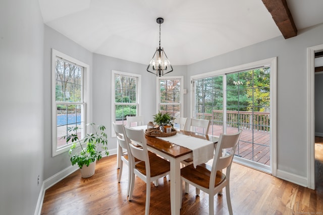 dining room with a chandelier, beam ceiling, and light hardwood / wood-style flooring