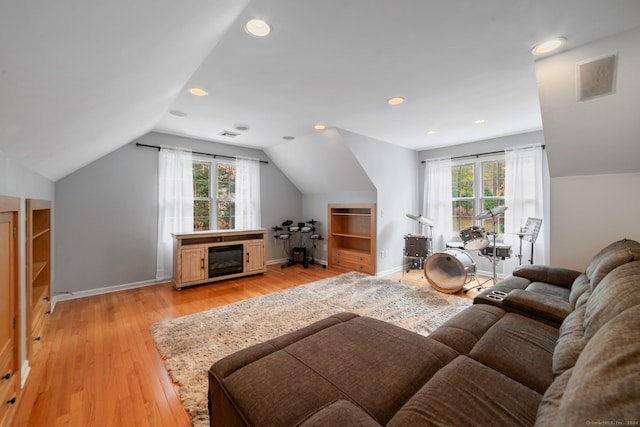 living room with a wealth of natural light, light hardwood / wood-style floors, and lofted ceiling