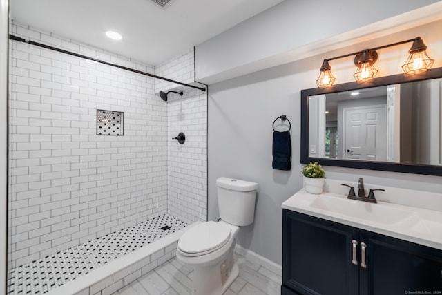 bathroom featuring tiled shower, vanity, and toilet