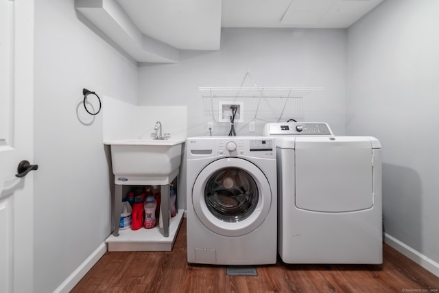 clothes washing area featuring washer and clothes dryer, dark hardwood / wood-style flooring, and sink