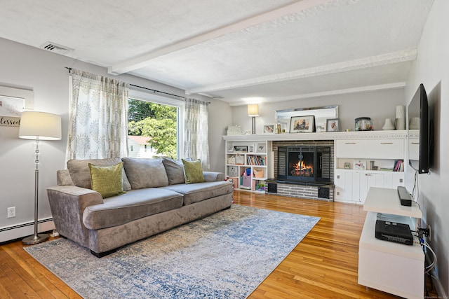 living area featuring a baseboard radiator, visible vents, a brick fireplace, beam ceiling, and light wood finished floors