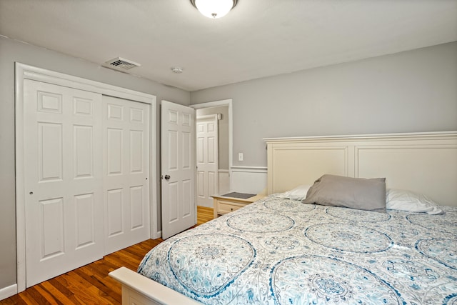 bedroom with a closet, dark wood finished floors, and visible vents