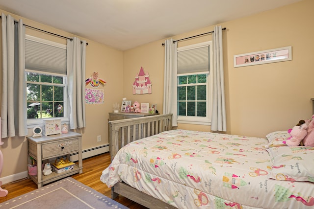 bedroom featuring a baseboard radiator, baseboards, and wood finished floors