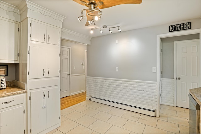 kitchen featuring white cabinetry, a wainscoted wall, baseboard heating, and light tile patterned floors