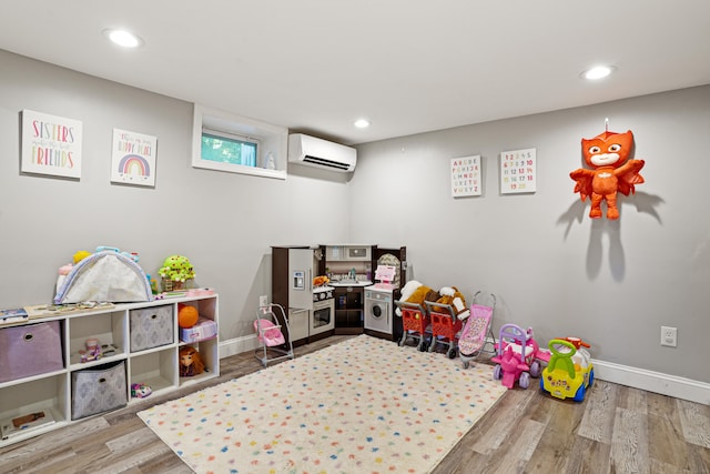 recreation room featuring recessed lighting, an AC wall unit, baseboards, and wood finished floors