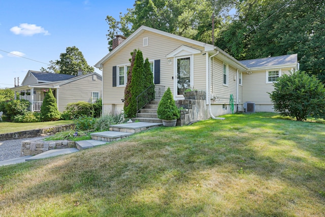 view of front of home with a front lawn, a chimney, and cooling unit