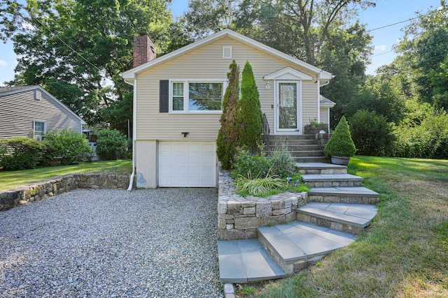 view of front facade with an attached garage, driveway, a chimney, and a front yard