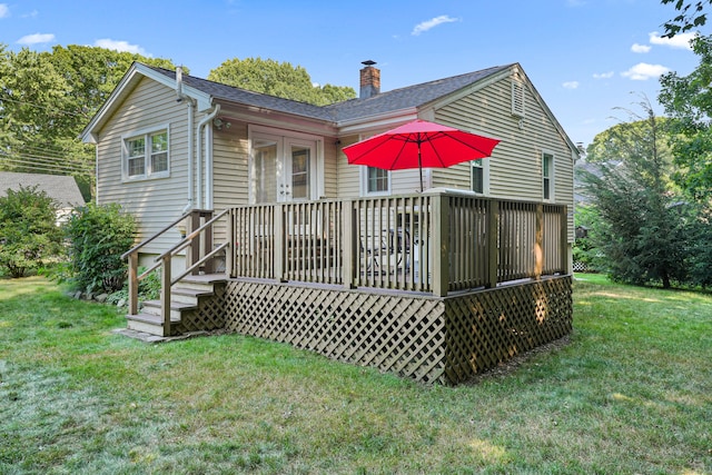 rear view of house featuring french doors, a chimney, a shingled roof, a lawn, and a wooden deck