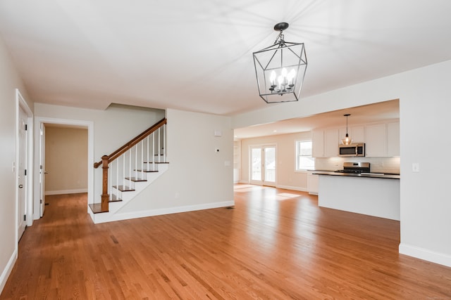 unfurnished living room with wood-type flooring and a notable chandelier