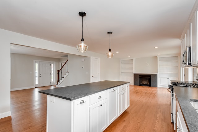 kitchen with a center island, light hardwood / wood-style flooring, white cabinets, and decorative light fixtures