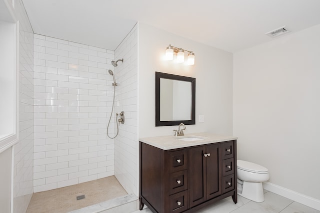 bathroom with tile patterned floors, vanity, a tile shower, and toilet