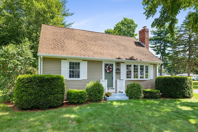 view of front of property featuring a chimney, a front lawn, and a shingled roof