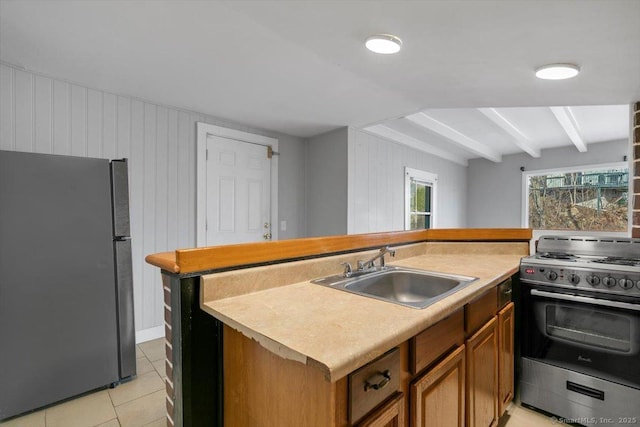 kitchen with light tile patterned flooring, appliances with stainless steel finishes, wood walls, and sink