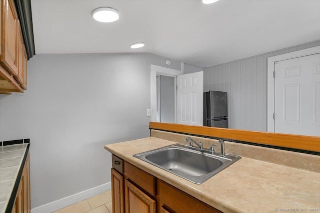 kitchen with light tile patterned flooring, sink, and black fridge