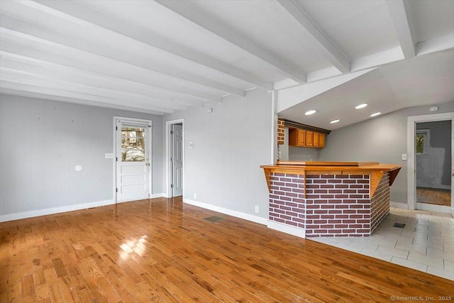 bar with light hardwood / wood-style floors and beamed ceiling