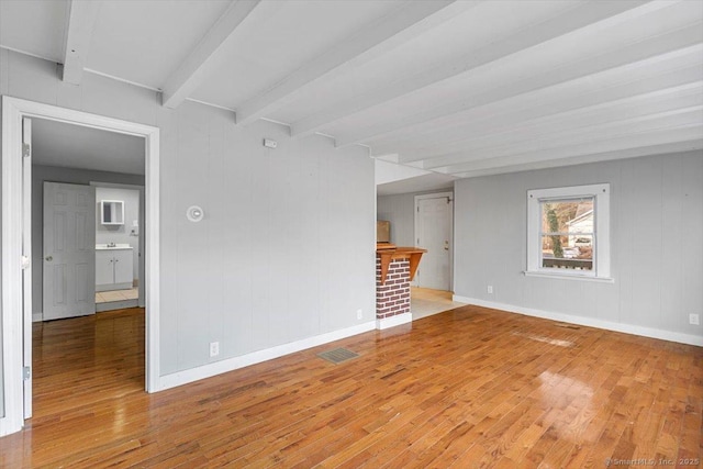 empty room with hardwood / wood-style flooring and beamed ceiling