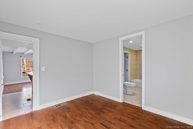 unfurnished room featuring beam ceiling and hardwood / wood-style floors