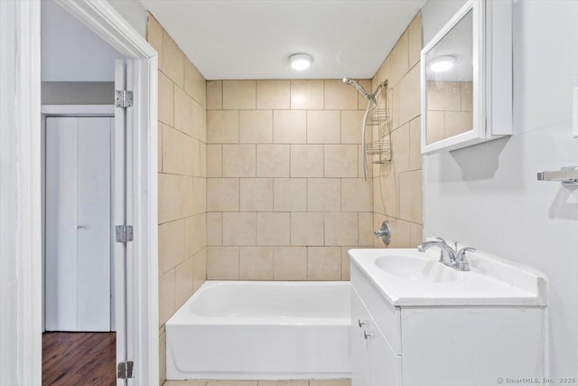 bathroom with tiled shower / bath combo, hardwood / wood-style floors, and vanity