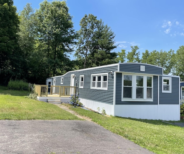 manufactured / mobile home with a wooden deck and a front lawn