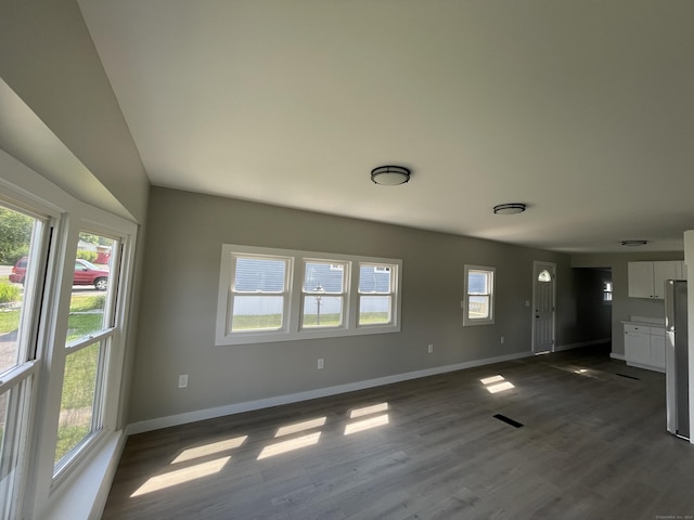 unfurnished living room featuring dark wood-type flooring and a wealth of natural light