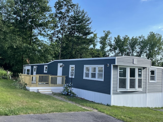 manufactured / mobile home featuring a wooden deck and a front yard