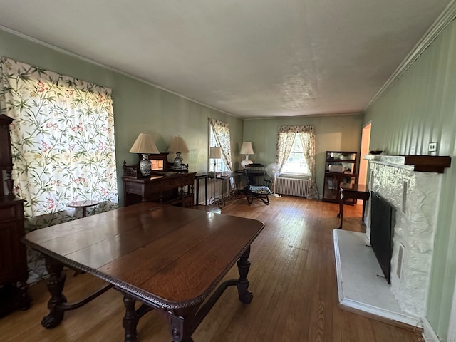 interior space with ornamental molding, radiator heating unit, a fireplace, and wood-type flooring