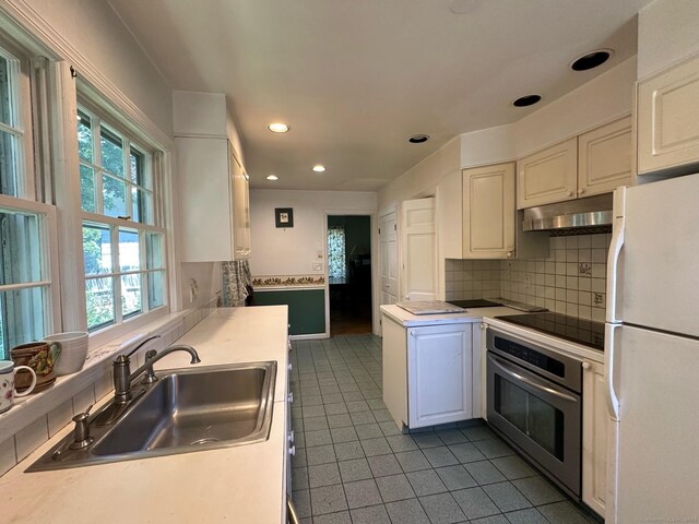 kitchen with tasteful backsplash, sink, stainless steel oven, light tile patterned flooring, and white fridge