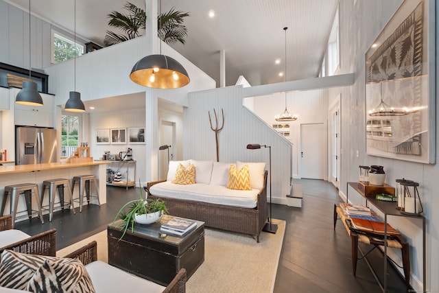 living room featuring a wealth of natural light, high vaulted ceiling, dark hardwood / wood-style floors, and a notable chandelier