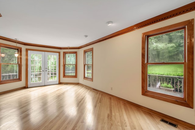 unfurnished room featuring crown molding, light wood-type flooring, and french doors