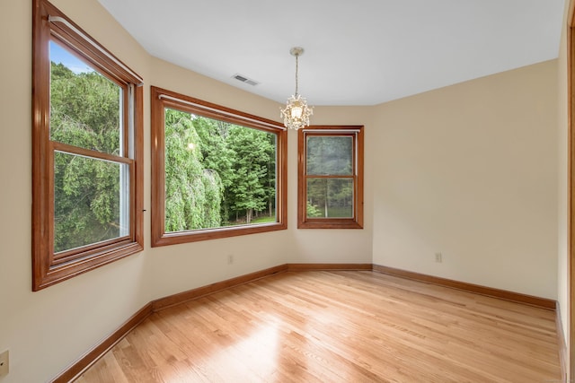 spare room featuring light hardwood / wood-style flooring and a chandelier