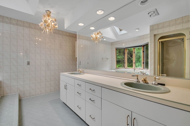 bathroom featuring a skylight, tile walls, tile patterned flooring, vanity, and a notable chandelier