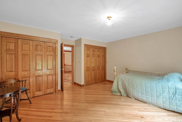 bedroom featuring two closets and light hardwood / wood-style floors