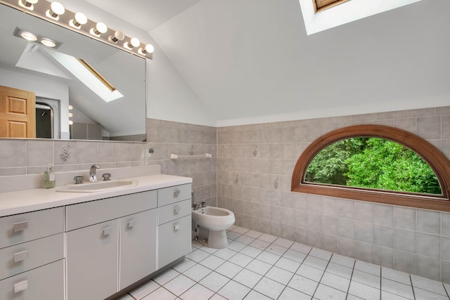 bathroom featuring a bidet, tile walls, tile patterned flooring, lofted ceiling with skylight, and vanity