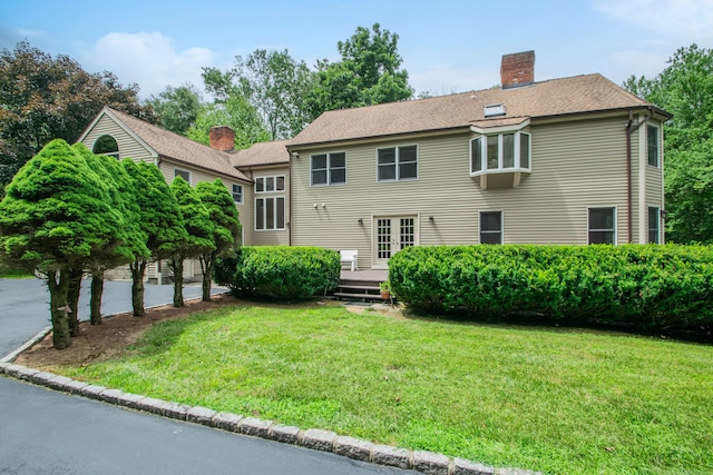 back of property featuring a wooden deck, a yard, and french doors