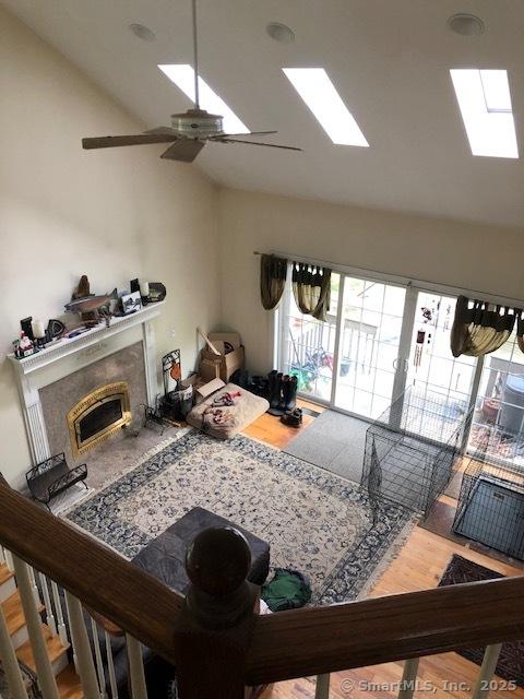 46 Nedobity Rd, Haddam, CT 06441 - living room featuring vaulted ceiling, a skylight, wood finished floors, ceiling fan, and a glass covered fireplace