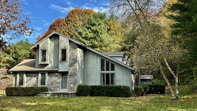 view of side of home featuring stone siding and a lawn