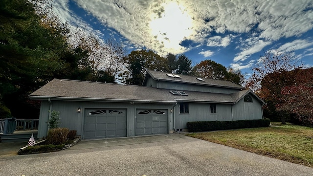 view of side of home featuring a lawn, driveway, and a garage