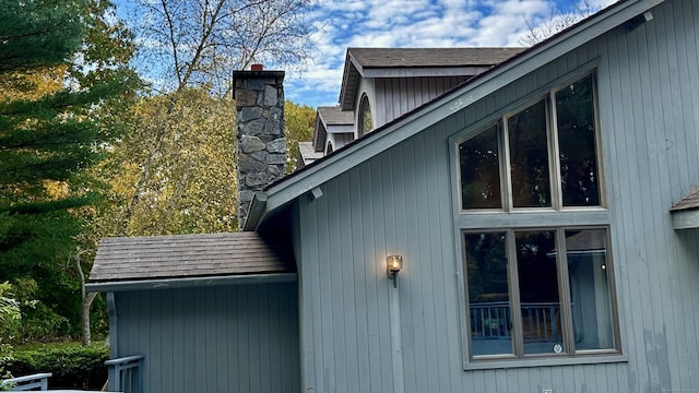 view of side of property featuring roof with shingles and a chimney