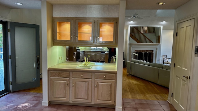 kitchen featuring light tile patterned flooring, ceiling fan, light countertops, glass insert cabinets, and a baseboard heating unit