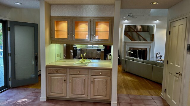 162 Pequot Trl, Stonington, CT 06379 - kitchen with ceiling fan, light countertops, a sink, light tile patterned floors, and glass insert cabinets